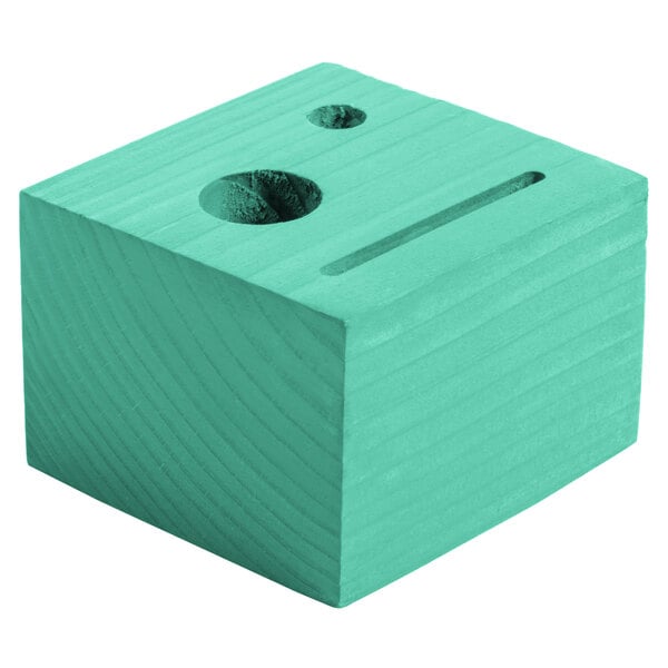 A teal wood block with a cross-shaped hole.