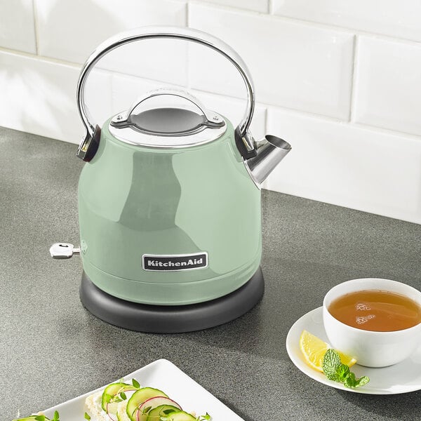 A KitchenAid stainless steel electric kettle with tea and lemon on a counter.