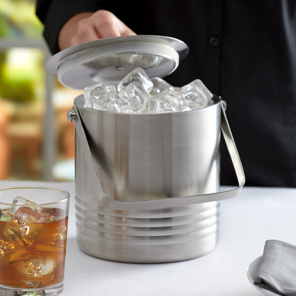 A man putting ice in a Tablecraft stainless steel ice bucket.