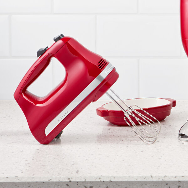 A red KitchenAid 5-speed hand mixer with stainless steel beaters.