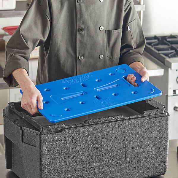 A person using a blue rectangular Camchiller in a blue plastic tray.