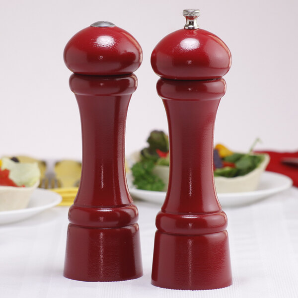 A red Chef Specialties pepper mill and salt shaker on a table.