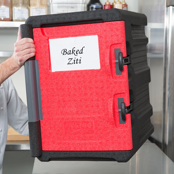 A man holding a red and black Metro Mightylite pan carrier kit.
