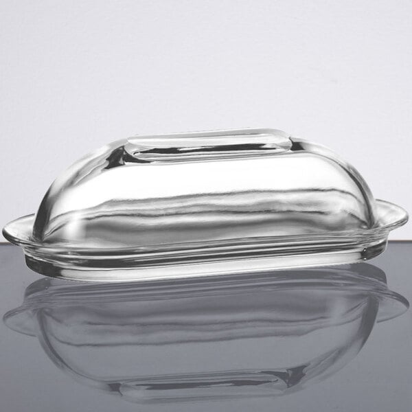 A clear glass Anchor Hocking butter dish with a lid.