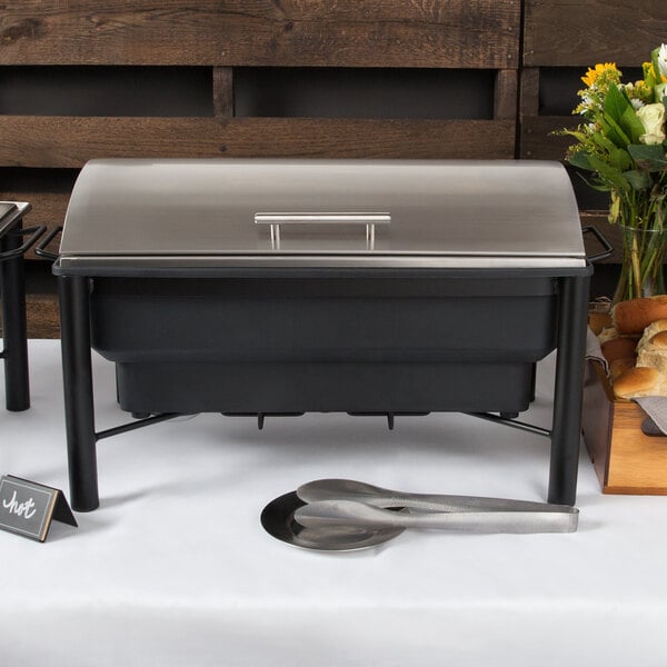 An Acopa wrought iron electric chafer on a buffet table with utensils.