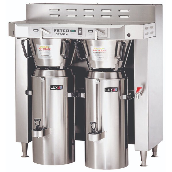 A Fetco stainless steel twin automatic coffee brewer with two large silver containers.