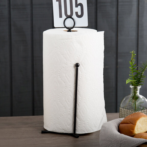 An American Metalcraft black curved wire paper towel holder with a card holder on a table with a roll of paper towels.