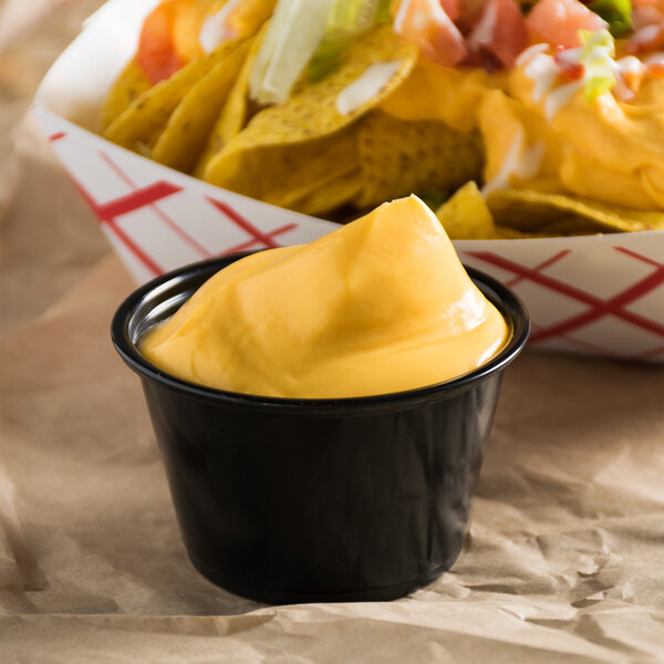 A bowl of nachos with Gehl's yellow cheese sauce next to a bowl of cheese dip.