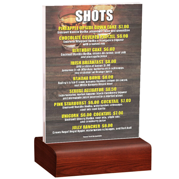 A Menu Solutions clear acrylic table tent with mahogany wood base holding a drink menu on a wooden table.
