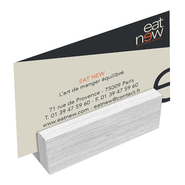A Menu Solutions white wash wood mini card holder with a business card in it.