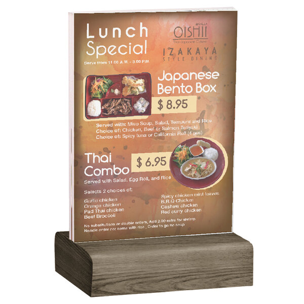 A Menu Solutions clear acrylic table tent with a weathered walnut wood base holding a menu on a table.