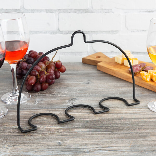 A black metal Vollrath wine glass holder on a table with wine glasses.