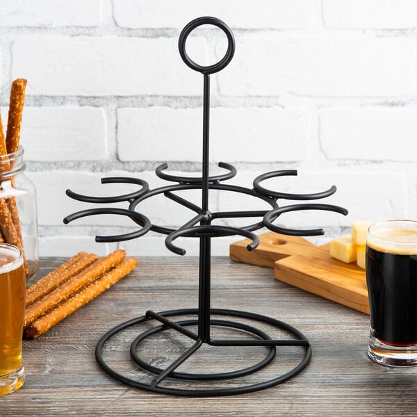 A black metal rack with Vollrath tasting glasses holding beer and snacks on a table.