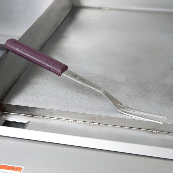 A Mercer Culinary Hell's Handle pot fork on a metal surface.