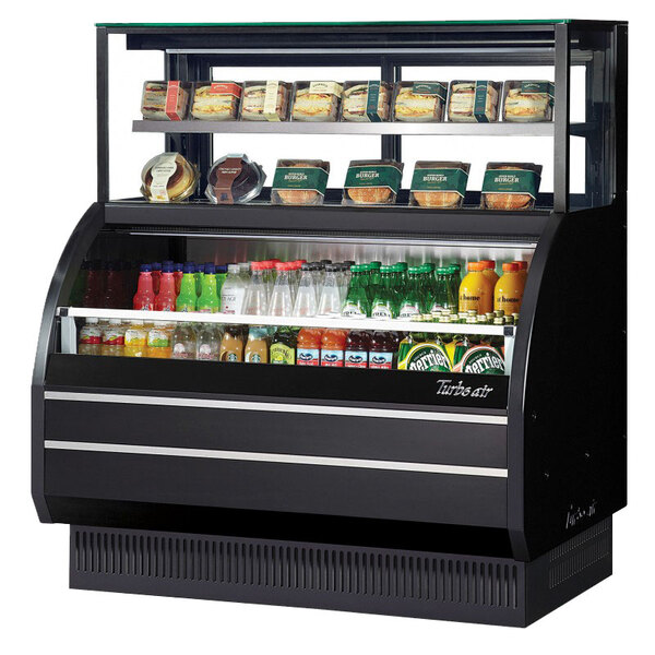 A white Turbo Air air curtain combination display case on a counter with food shelves full of various food items.