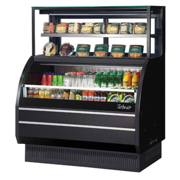 A black Turbo Air air curtain display case with food on shelves.