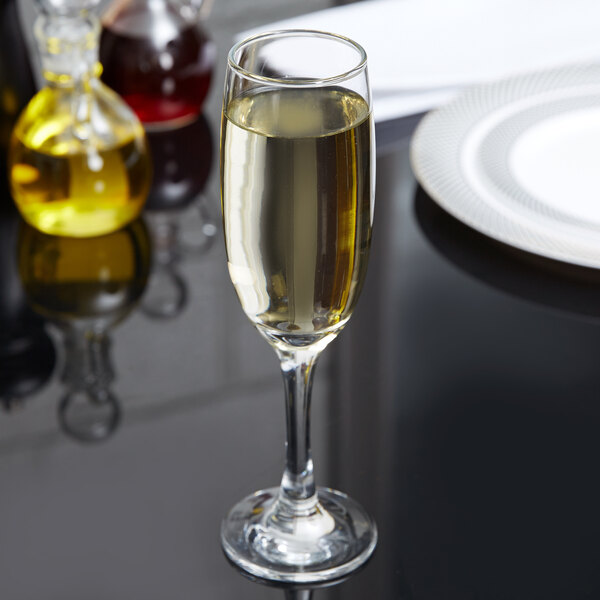 An Anchor Hocking Excellency flute glass filled with champagne on a table.