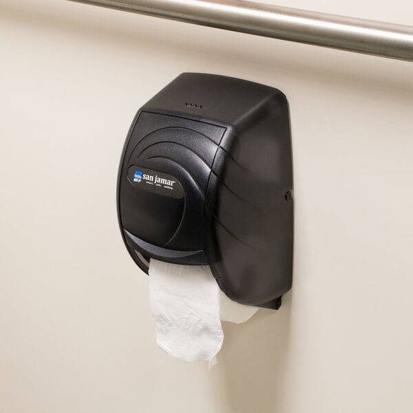 A black San Jamar Duett Oceans toilet tissue dispenser on a wall.
