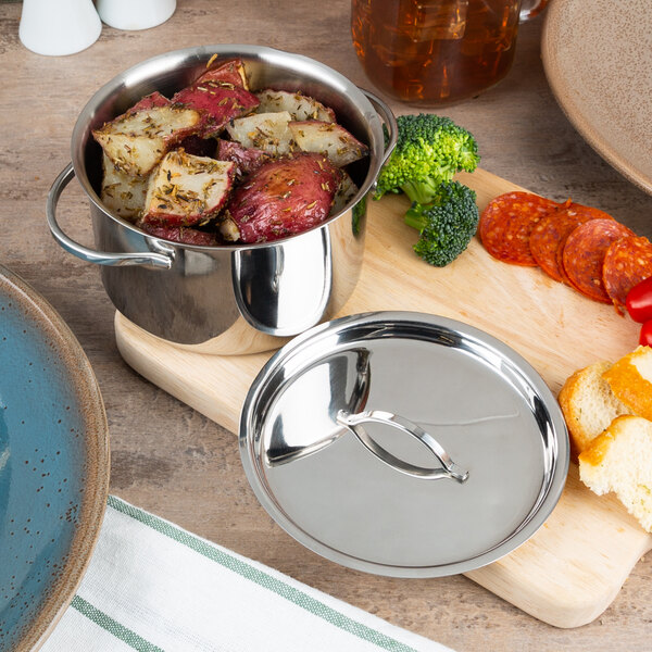A stainless steel American Metalcraft mini pot with a lid on a cutting board filled with potatoes and vegetables.