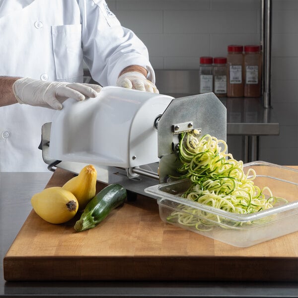 A chef using a Nemco Powerkut vegetable noodler to make zucchini noodles.