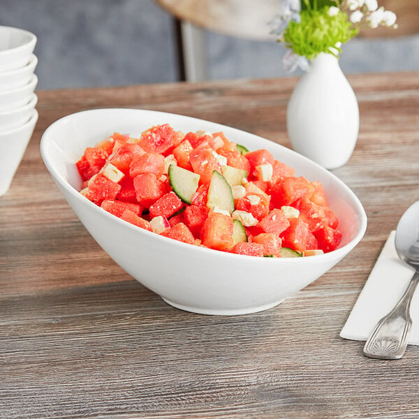 A close up of a white slanted porcelain bowl filled with watermelon and cucumber salad.