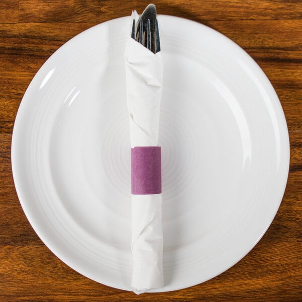 A burgundy and white napkin wrapped around a fork and knife on a white plate.
