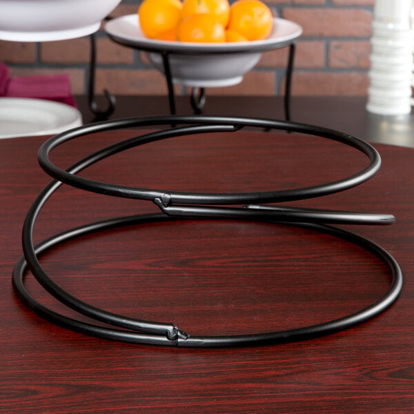 An American Metalcraft wrought iron riser with a bowl of oranges on it.