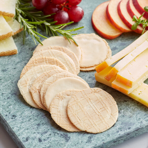 A plate with sliced apple, cheese, grapes, and 3.5 oz. Wafer Thin Crackers on a marble surface.