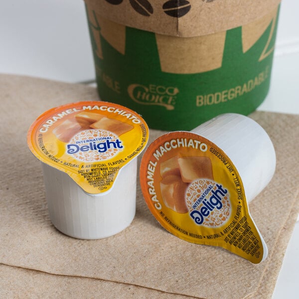 Two cups of coffee with International Delight Caramel Macchiato creamer on a table in a coffee shop.