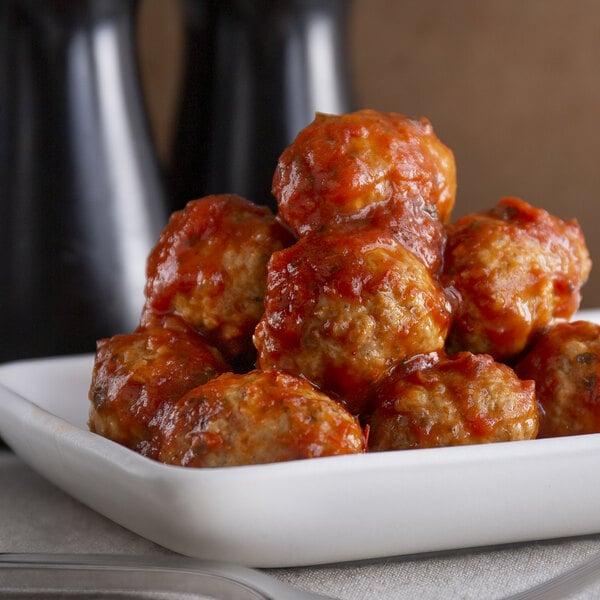A close up of Spring Glen Fresh Foods meatballs in marinara sauce on a white plate.