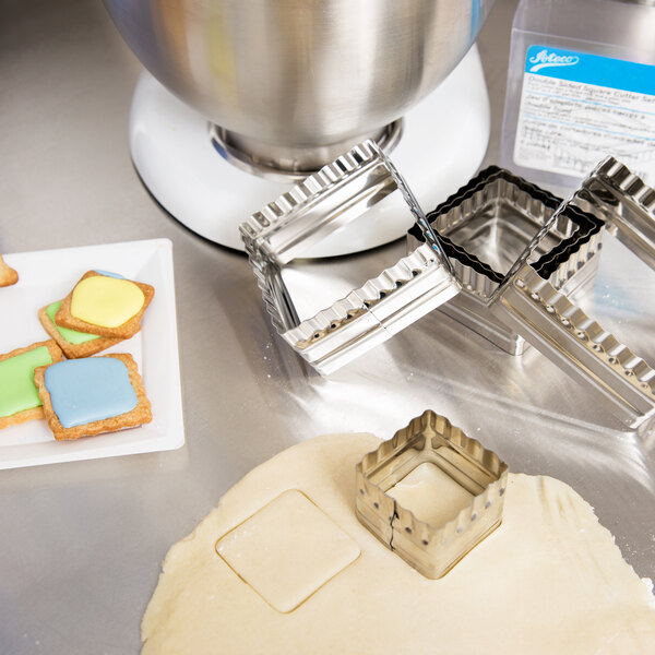 A stainless steel Ateco square cookie cutter and cookie dough.