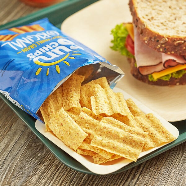 A sandwich on a plate with a bag of Sun Chips.