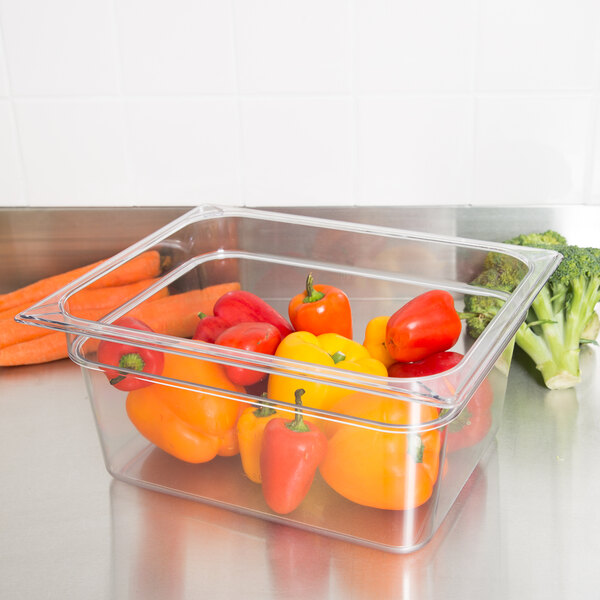 A Carlisle clear polycarbonate food pan filled with broccoli on a counter.
