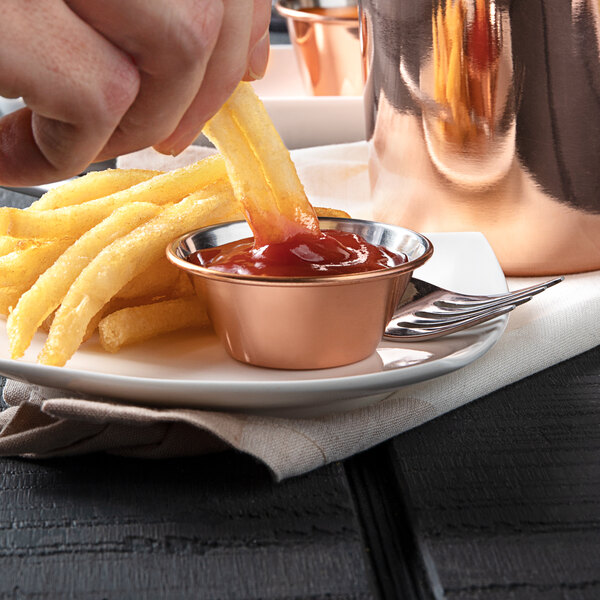 A hand dipping a french fries into a Choice copper sauce cup.