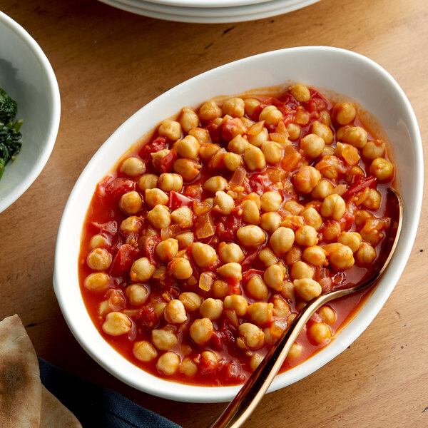 A bowl of Bella Vista chickpeas with a spoon on a table.