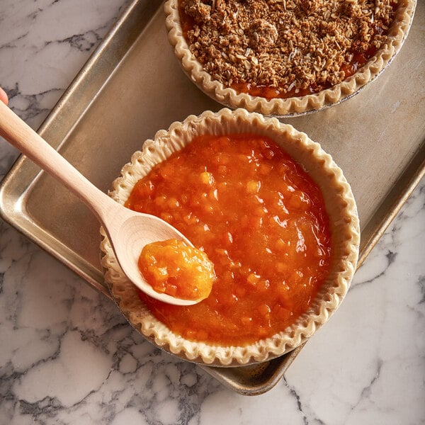 A wooden spoon in a pie filled with Lawrence Foods peach pie filling.