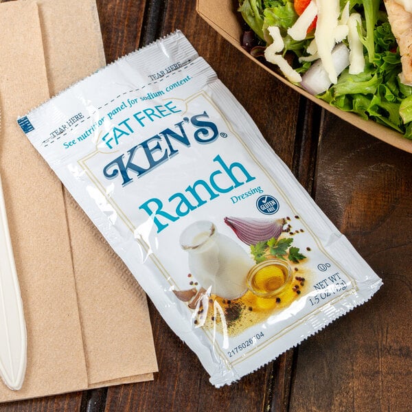 A salad with a packet of Ken's Fat Free Ranch dressing.