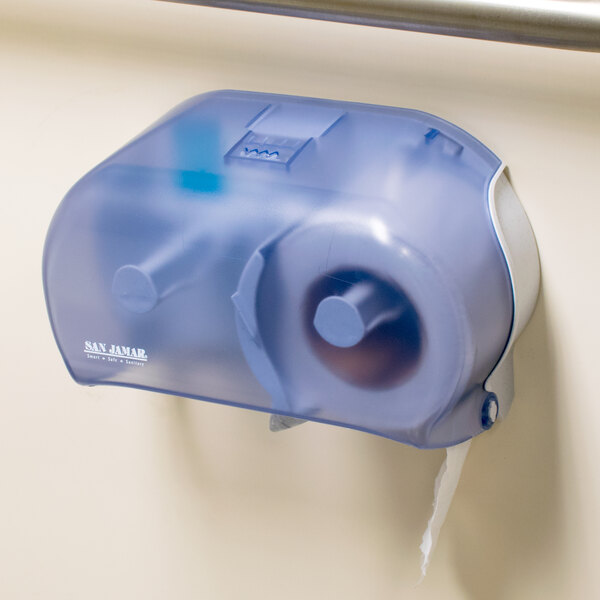 A San Jamar Versatwin double roll toilet paper dispenser in arctic blue on a wall.