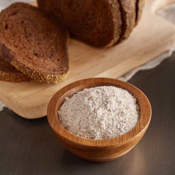 A bowl of Ardent Mills medium rye meal pumpernickel flour next to slices of bread.