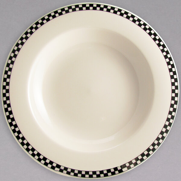 A creamy white china pasta bowl with black and white checkered trim.