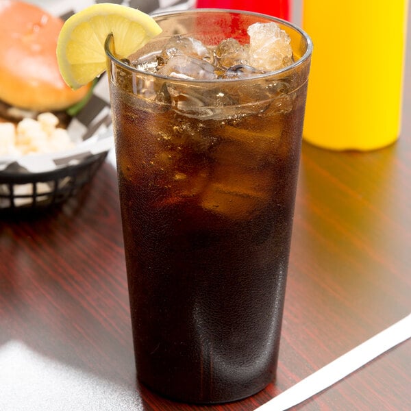 A Cambro amber plastic tumbler filled with iced tea and a lemon wedge.