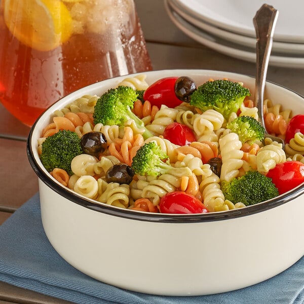 A bowl of Costa Pasta Rainbow Tri-Color Rotini with broccoli and olives on a table