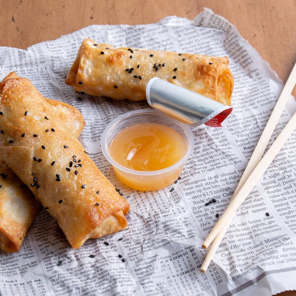 A plate of fried spring rolls with Ken's Foods Sweet & Sour Sauce on a white background.