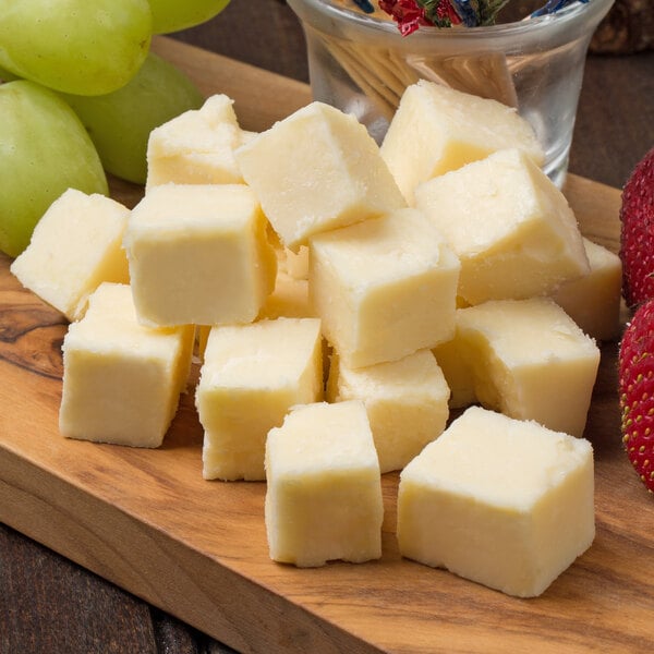 A group of Black Diamond extra sharp cheddar cheese cubes next to grapes and strawberries.
