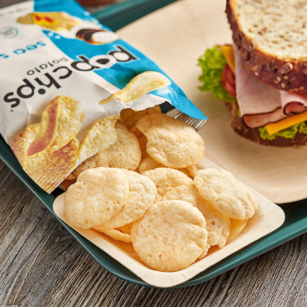 A tray with a plate of Popchips and a sandwich.