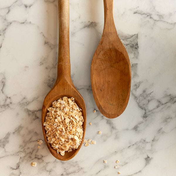 A wooden spoon with quick oats on a marble surface.
