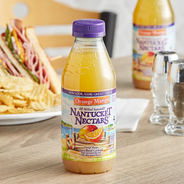 A close-up of a Nantucket Nectars Orange Mango Juice Cocktail bottle on a table.