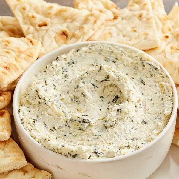 A bowl of Artichoke Asiago cream cheese spread with crackers.