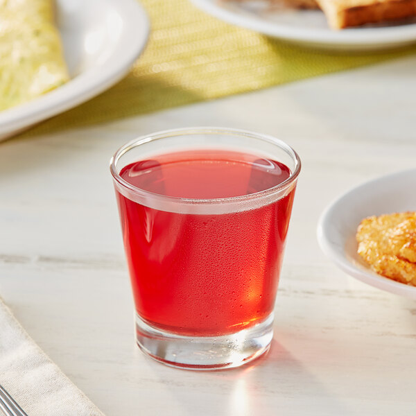 A glass of Ocean Spray Cranberry Juice Cocktail on a table with food.