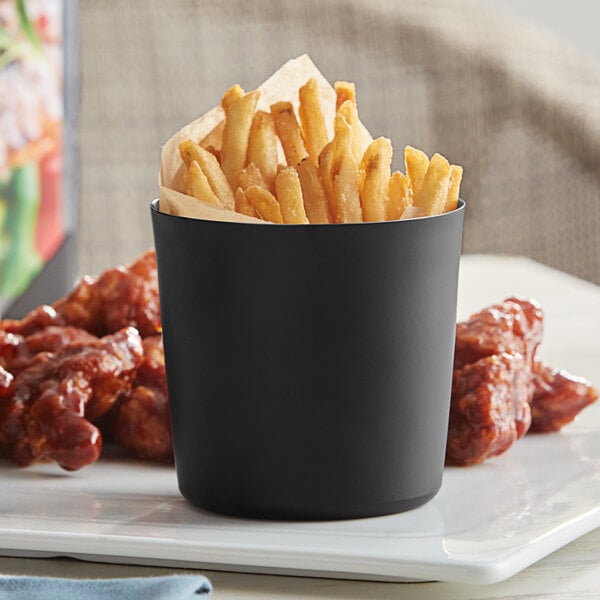 An Acopa matte black stainless steel container with french fries and chicken wings on a white plate.